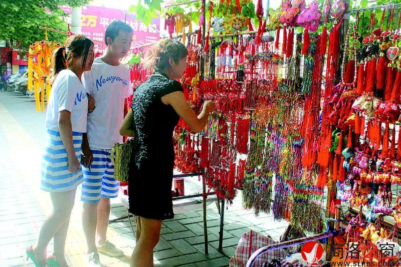 文化廣場(chǎng)香包攤前造型各異、做工精美的香包吸引年輕人購(gòu)買。