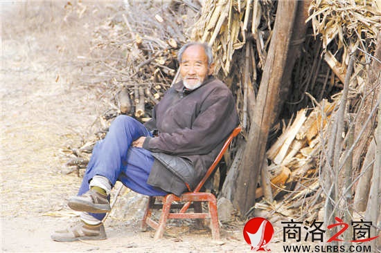 花白胡子的趙恩老人靠著柴垛悠閑地聽著秦腔戲