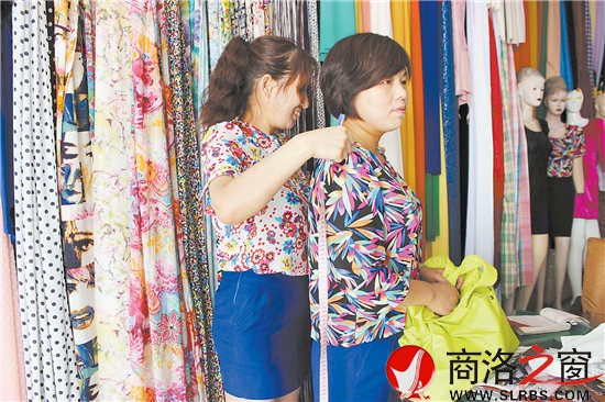 雷小莉仔細(xì)地為客人量尺寸，量體裁衣是裁縫鋪?zhàn)畲蟮膬?yōu)勢。